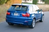 Driving 2013 BMW X5 M in Monte Carlo Blue Metallic from a rear right three-quarter view